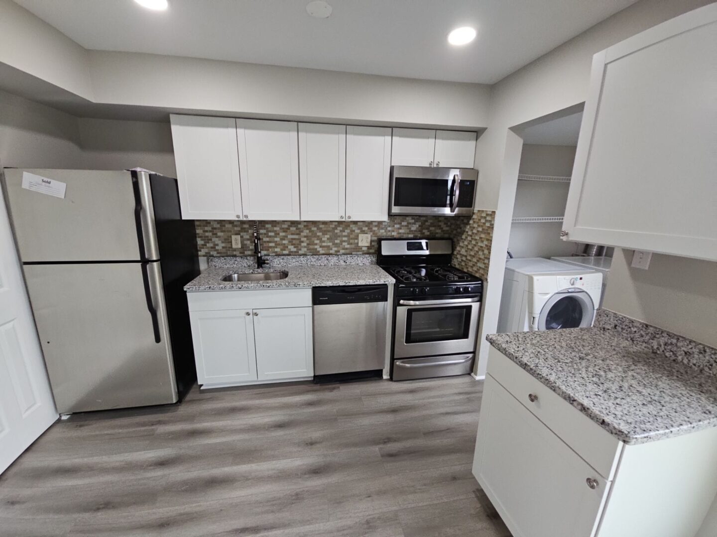 A kitchen with white cabinets and appliances in it