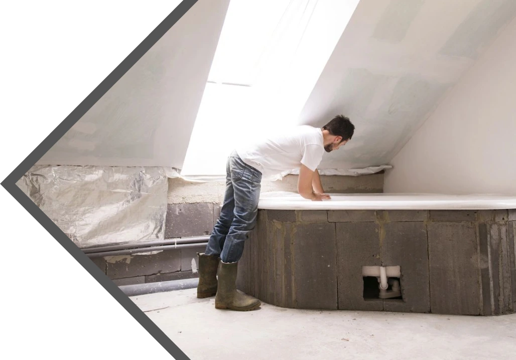 A man in white shirt and boots working on a wall.