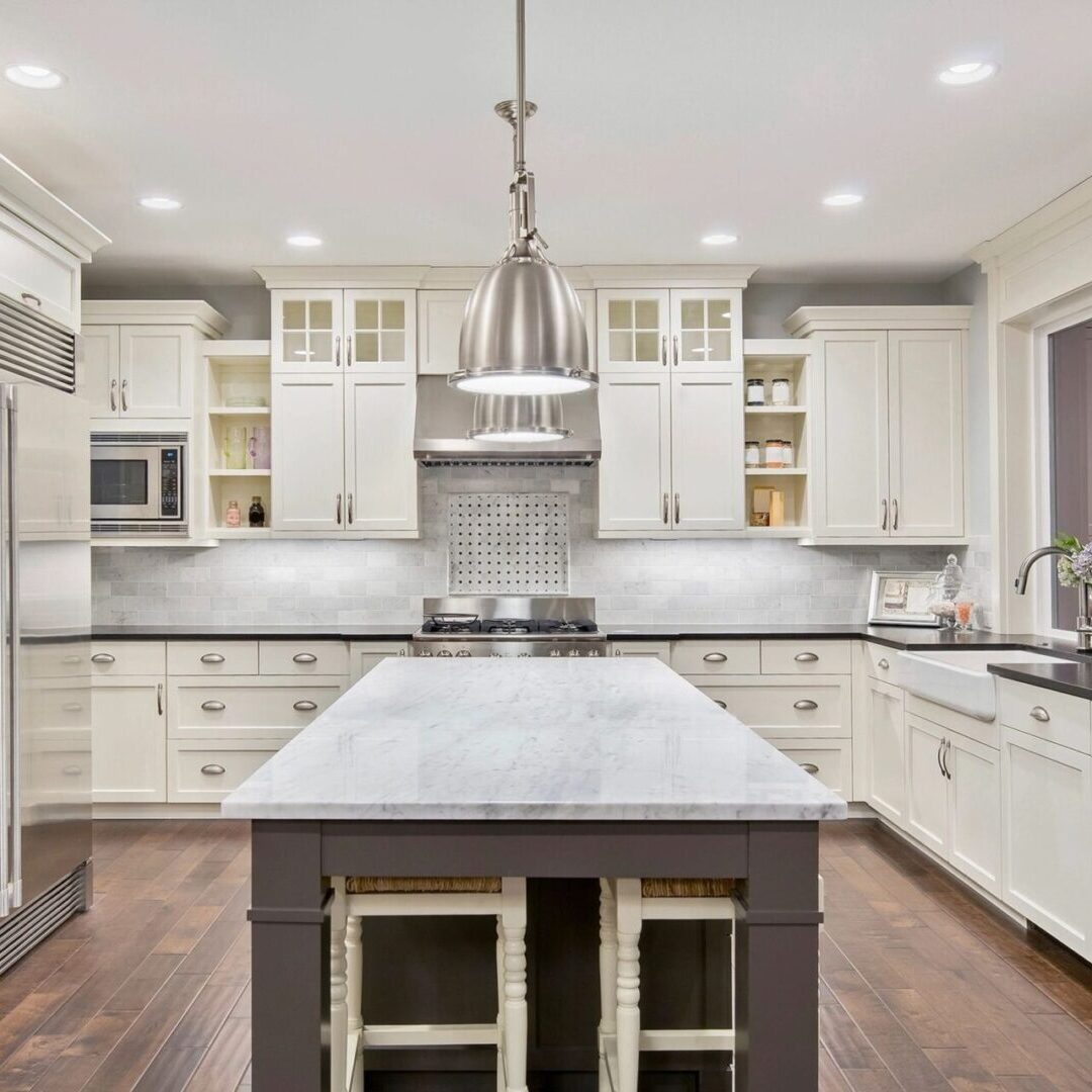 A large kitchen with white cabinets and wooden floors.