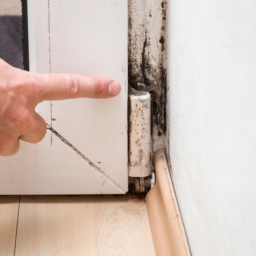 A person points to the wall of their home.